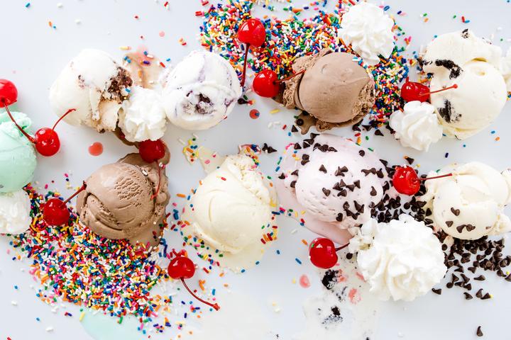 Assorted ice cream scoops with cherries, whipped cream, sprinkles, and chocolate chips
