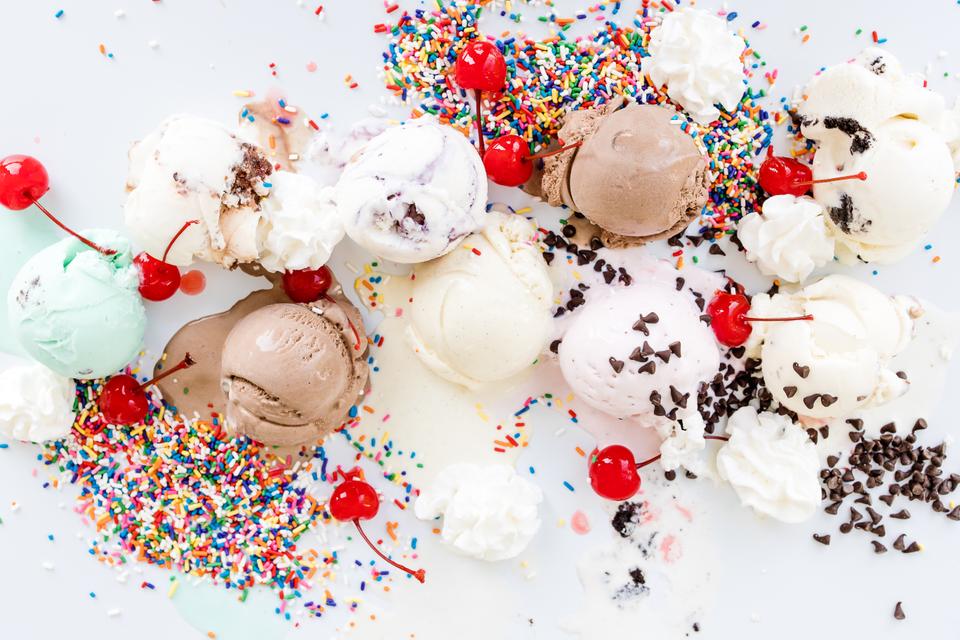 Assorted ice cream scoops with cherries, whipped cream, sprinkles, and chocolate chips